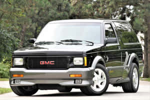 黑色GMC Safari SUV停放在綠樹成蔭的道路上。 — 低調 壁紙