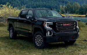 黑色GMC Sierra AT4 pickup truck停泊在靠近森林和河流的草地上。