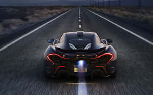 黑色McLaren P1在黃昏時分在沙漠高速公路上飛馳，帶有發光燈光。 — 好看汽車 壁紙