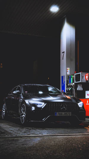 夜間在明亮燈光下的加油站油泵旁的黑色Mercedes-AMG。 — 瓦斯 壁紙
