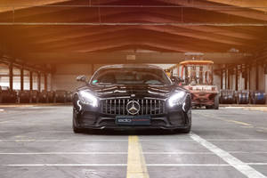 黑色Mercedes-AMG GT R停放在工業倉庫內，背景有堆高機。 — Mercedes-Benz 壁紙