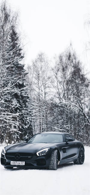 黑色跑車停放在白雪覆蓋的森林中，周圍是積雪的樹木。 — 汽車 iPhone 壁紙