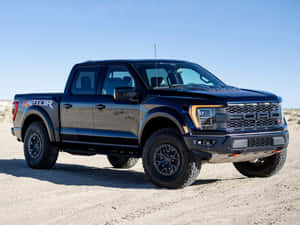 黑色福特 F-150 Raptor 皮卡車停放在烈日下的沙漠碎石上。 — 福特 壁紙