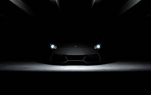 黑色藍寶堅尼 Aventador 在戲劇性攝影棚燈光下的正面視圖。 — 純黑 壁紙