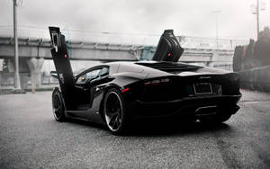 黑色藍寶堅尼 Aventador 在都市道路上打開鷗翼車門，黃昏時分。 — 跑車 壁紙