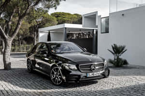 黑色賓士轎車停泊在現代白色房屋前，背景有樹木。 — Mercedes Benz C300 壁紙