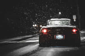 黑色跑車在夜間雪中行駛，帶有紅色尾燈。 — JDM風格 壁紙