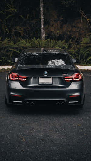 黑色BMW M4跑車，紅色尾燈，停在森林中。 — 昏暗 壁紙