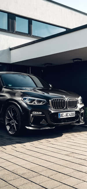 黑色BMW X5停放在現代房屋前的石頭車道上。 — Xiaomi 14 壁紙