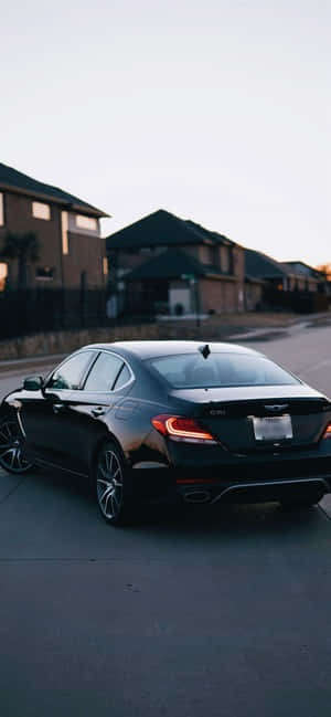 黑色Genesis G70轎車停放在住宅區街道上（黃昏）。 — Galaxy S25 FE 壁紙