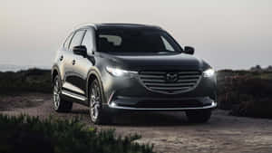 黑色Mazda CX-9 SUV停泊在塵土小徑上，車頭燈亮著 — 馬自達 壁紙