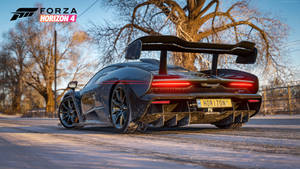 黑色McLaren跑車停泊在雪路上，周圍是光禿禿的樹木，夕陽西下。 — 電玩遊戲 GIF 壁紙