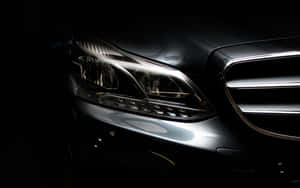 在昏暗工作室燈光下，豪華汽車車頭燈和格柵的特寫。 — Mercedes Benz C300 壁紙