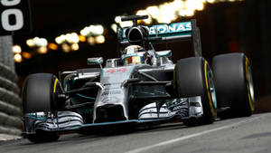 梅賽德斯一級方程式賽車在夜間賽道奔馳，伴隨城市燈光。 — F1 iPhone 壁紙
