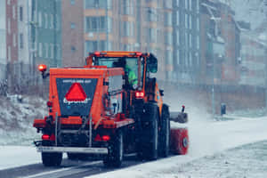 橙色鏟雪車在冬季清理城市街道上的積雪。 — MacBook Air 13 壁紙