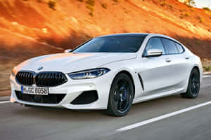 白色BMW 8系列轎跑車在日落時分的風景道路上疾馳。 — 凱迪拉克 壁紙