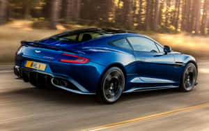 藍色 Aston Martin Vanquish 在日落時分的森林道路上疾馳。 — 阿斯頓維拉 壁紙