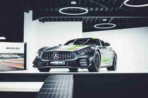 銀色AMG GT賽車帶有綠色條紋，在現代工作室中展示。 — Mercedes Benz C300 壁紙