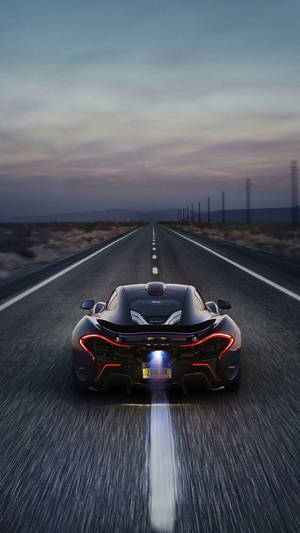 黑色跑車在黃昏時分在沙漠高速公路上疾馳，帶有發光的燈光。