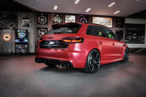 消光紅色ABT奧迪RS3 Sportback在高級汽車展間中，展示遊戲機和輪圈。 — Surface Pro 壁紙