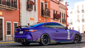 紫色BMW M4雙門跑車停在色彩繽紛的街道上，建築風格為地中海式。 — 極高畫質 壁紙