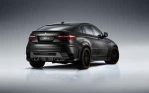消光黑色BMW X6M，橙色輪圈和四出排氣管，在攝影棚中反射。 — Steam Deck OLED 壁紙