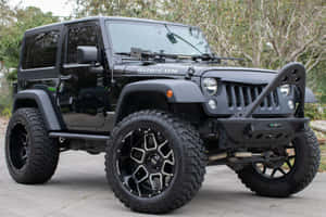 黑色Jeep Rubicon SUV配備大型越野輪胎停放在戶外。 — 吉普 壁紙