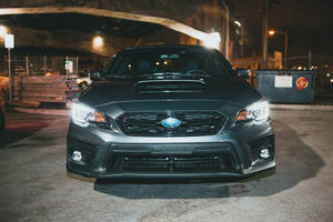 夜晚，黑色Subaru WRX STI停在城市高架橋下，車頭燈亮著。 — 昴 壁紙