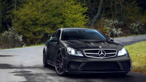 林間道路上的消光黑色梅賽德斯-AMG跑車。 — Mercedes Benz C300 壁紙