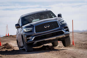 深灰色 Infiniti SUV 在設有橙色三角錐的泥土障礙賽道上行駛。 — Surface Pro 壁紙