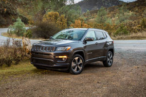 深灰色Jeep Compass停泊在秋日山丘彎路附近的碎石上。 — 吉普 壁紙
