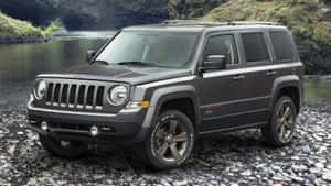 深灰色Jeep Patriot SUV停泊在水邊的河石上。 — 吉普 壁紙