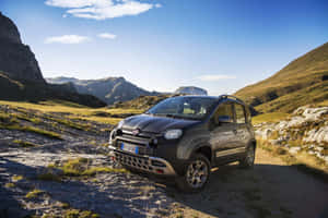 深灰色Fiat Panda Cross在岩石地形和綠色山丘的山徑上。 — 可愛熊貓 壁紙