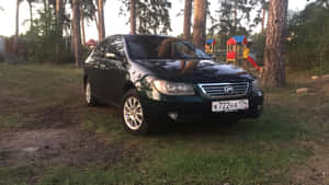 深綠色轎車停在松樹和遊樂場附近的草地上，黃昏時分。 — 黃昏 壁紙