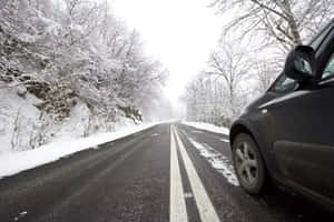深色汽車停泊在積雪的道路上，周圍是冬季被雪覆蓋的樹木。 — 冬季風景 壁紙