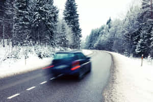 一輛汽車在白雪覆蓋的松樹林間道路上疾馳。 — 冬季風景 壁紙