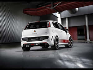 白色 Abarth Punto EVO 跑車在工業車庫內，帶紅色點綴和拋光地板。 — 好看汽車 壁紙