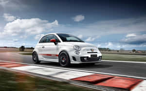 白色 Fiat Abarth 賽車在賽道上疾馳，帶有動態模糊效果。 — 2560x1600 壁紙