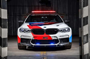 白色BMW M5安全車，帶有紅藍色條紋和閃爍燈光，在車庫中。 — Surface Pro 壁紙