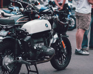 白色BMW摩托車，安全帽掛在把手，街上與其他摩托車一起停放。 — 巴布風機車 壁紙