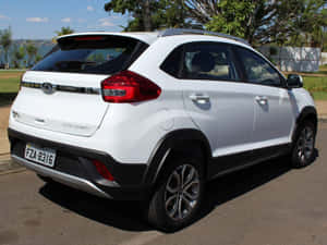 白色Chery Tiggo 3x SUV停放在靠近水和樹木的陽光明媚街道上。 — 好看汽車 壁紙
