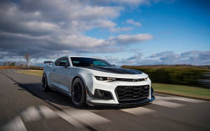 白色Chevrolet Camaro SS在多雲天空下於賽道上飛馳。 — 肌肉車 壁紙