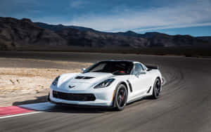 白色Corvette在沙漠賽道上與山脈和藍天競速