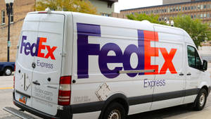 白色FedEx Express送貨車停放在城市街道上。 — 聯邦快遞 壁紙