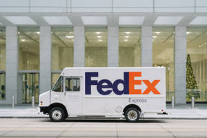 白色FedEx Express貨車停在現代建築外，建築內有聖誕樹。 — 墜落卡車 壁紙