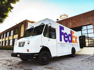白色FedEx Ground送貨車停在磚砌建築前。 — 聯邦快遞 壁紙