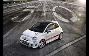 白色Fiat Abarth 500賽車在賽道上，帶有「50」標記，沐浴在金色夕陽光下。 — MacBook Air M1 壁紙