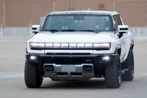 白色GMC Hummer EV SUV，在混凝土表面上頭燈亮起。 — 老福特卡車 壁紙