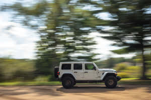 白色Jeep Rubicon在森林地區的泥路上行駛。 — 吉普 壁紙