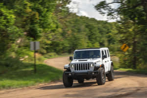 白色Jeep Wrangler在森林泥土路上快速行駛。 — 吉普 壁紙